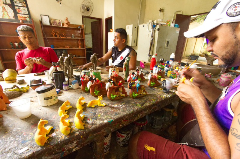 Local ceramic artists Alex, Hudson and Gustavo working on Pantanal-themed figurines at Casa do Massabarro.